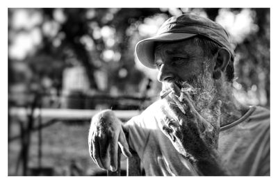 Senior man wearing cap while smoking cigarette outdoors