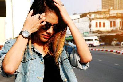 Young woman in sunglasses standing by road