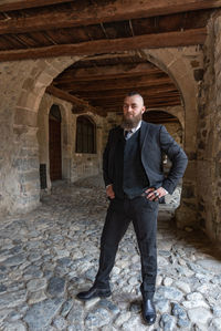 Full length portrait of man standing against stone wall