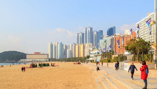 People on beach with city in background