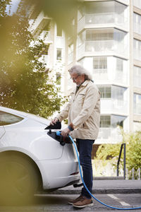 Senior man charging electric car