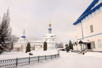 Road amidst buildings against sky during winter