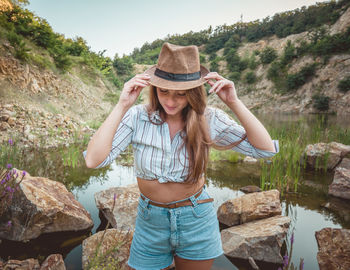 Portrait of smiling young woman standing on rock
