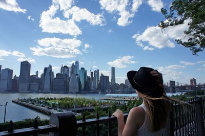 Rear view of woman by buildings against sky