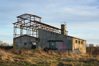 Abandoned factory on field against sky