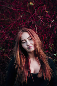 Young woman with eyes closed against plants