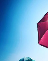 Low angle view of parasol against clear blue sky