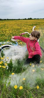 Rear view of woman with yellow flowers on field
