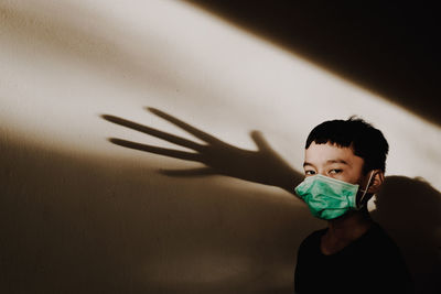 Portrait of boy with shadow on wall