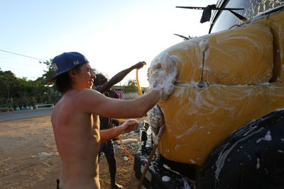 Side view of shirtless man with woman standing in water