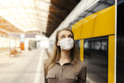 Woman wearing mask standing at railroad station