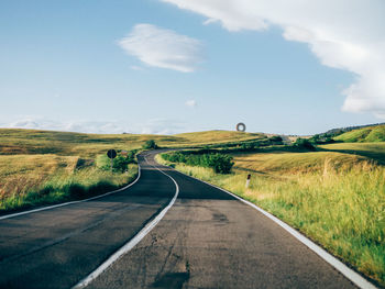 Road amidst field against sky