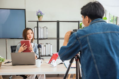 Side view of young woman using digital tablet while sitting in office