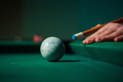 Cropped hand of person hitting pool ball with cue