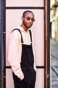 Portrait of young man standing against wall
