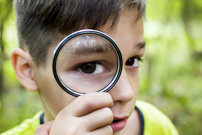 Close-up of boy looking through magnifying glass