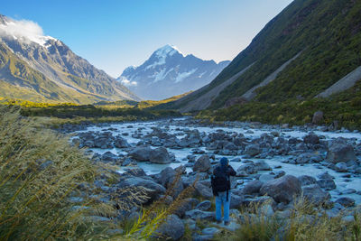 Rear view of man standing on mountain against sky