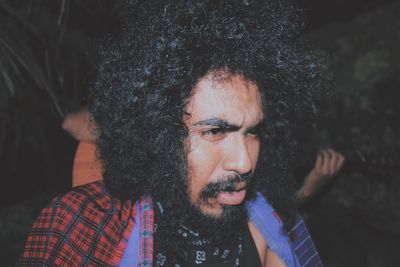 Close-up of man with curly hair looking away at night