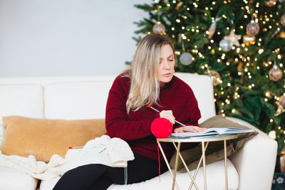 Young woman sitting with christmas tree