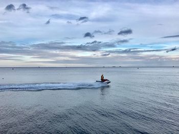 Person riding jet boat in sea against sky during sunset