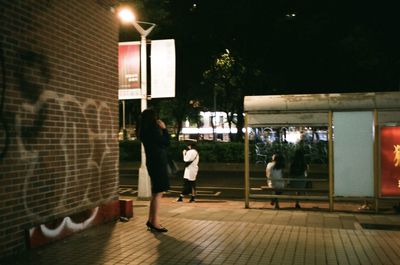 People walking on illuminated glass window at night