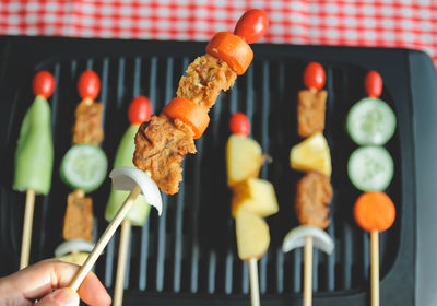 Cropped hand of man holding food over barbecue