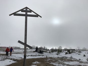 People on snow covered field against sky