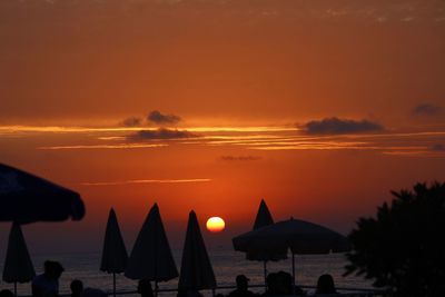 Silhouette people on beach against sky during sunset