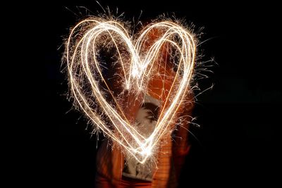 Person painting heart with sparklers at night