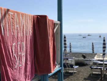 Clothes drying on wooden post at beach against sky