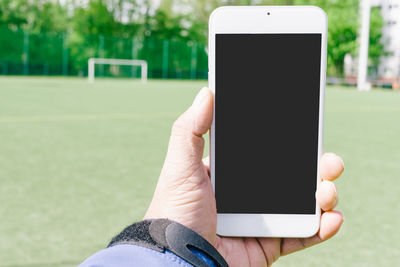 Midsection of person using mobile phone in park