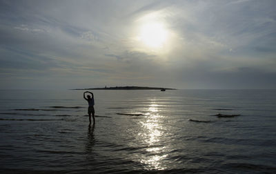 Silhouette person exercising on beach