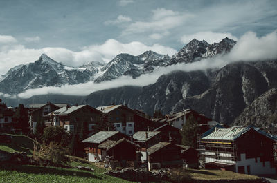 Houses by snowcapped mountains against sky