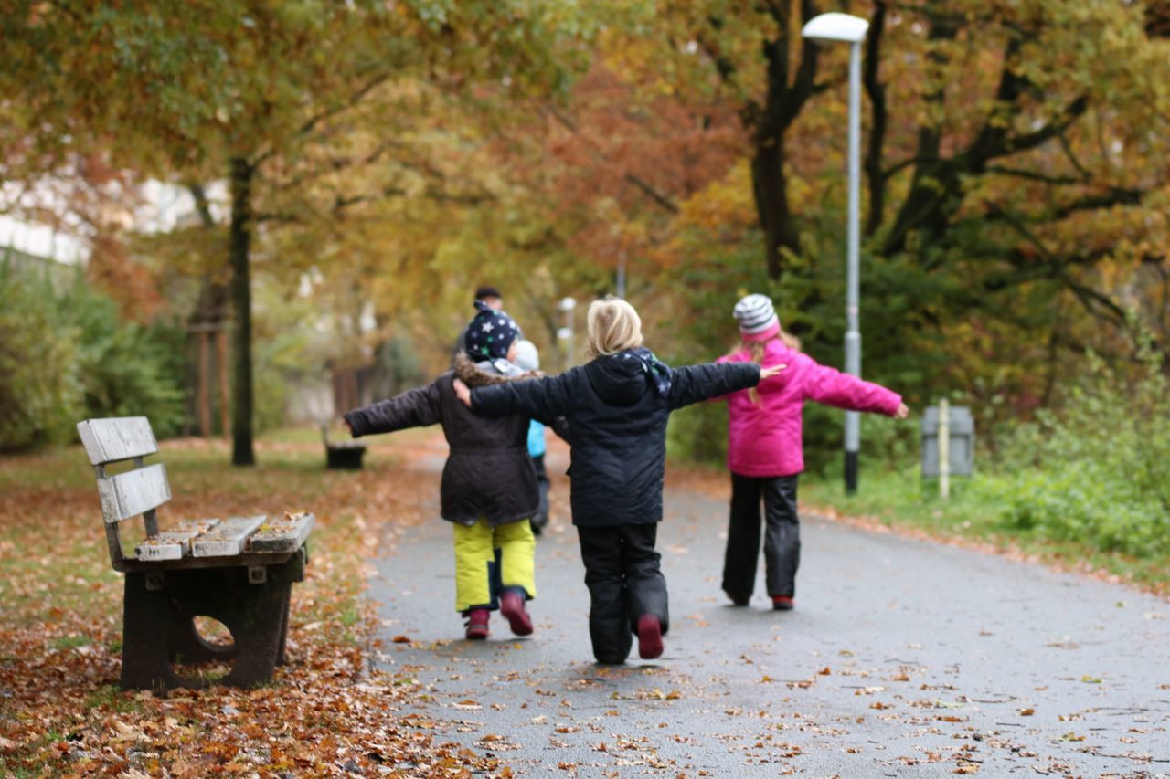 full length, fun, child, togetherness, tree, leisure activity, carefree, autumn, childhood, girls, people, knit hat, enjoyment, happiness, outdoors, warm clothing, healthy lifestyle, forest, recreational pursuit, playing, females, motion, adventure, bonding, cheerful, adult, day, nature, young adult, teamwork, headwear