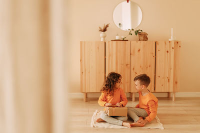 A little girl gives gift box to her brother congratulates him on the holiday  in the children's room