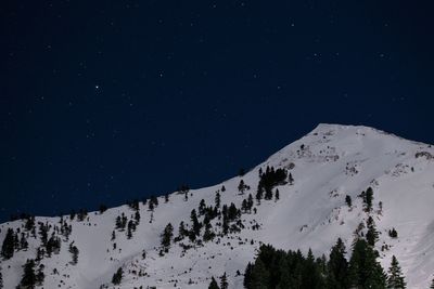 Low angle view of snowcapped mountains against clear sky at night