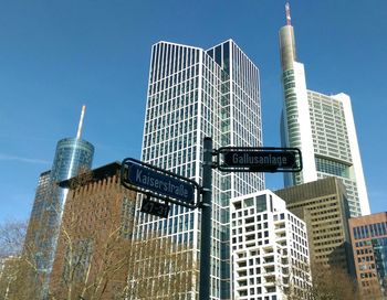 Low angle view of road sign against skyscrapers in city