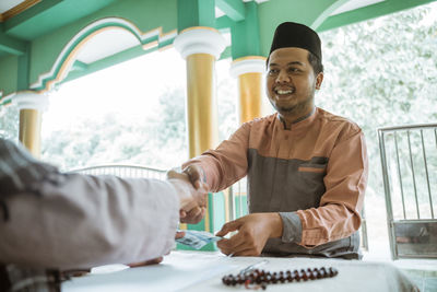 Happy young man shaking hand with friend at mosque