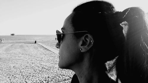 Portrait of young man wearing sunglasses at beach against clear sky