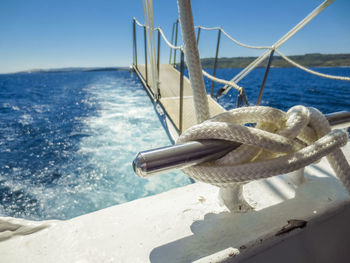 Close-up of rope tied to boat sailing in sea against sky
