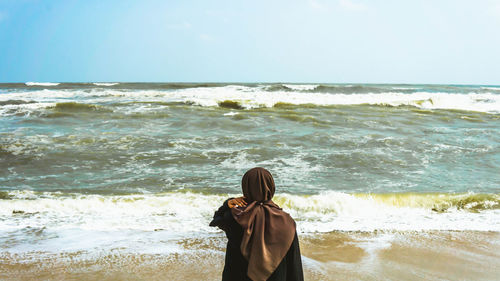 Rear view of man looking at sea against sky