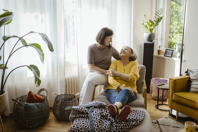 Smiling mature woman spending leisure time mother-in-law sitting on chair in living room at home