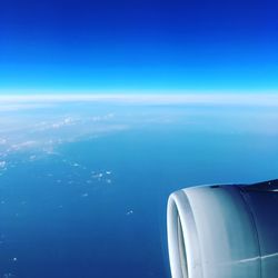 Airplane flying over sea against blue sky