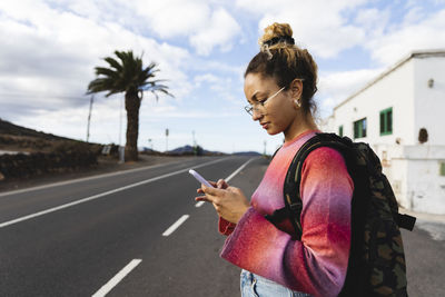 Young woman using mobile phone on roadside