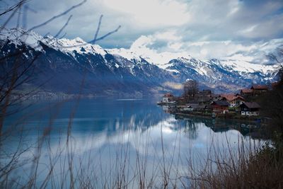 Scenic view of lake by buildings against sky during winter