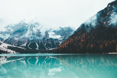 Scenic view of lake by snowcapped mountains against sky