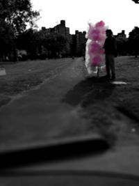 Rear view of woman walking on road against trees