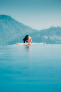 Rear view of woman swimming in sea against clear sky