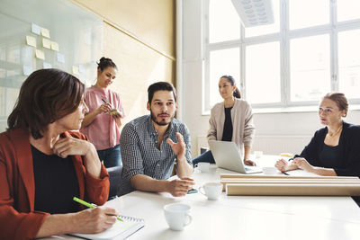 Businessman explaining new project to female colleagues at conference table