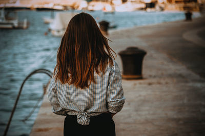 Rear view of teenage girl with long hair while standing at harbor